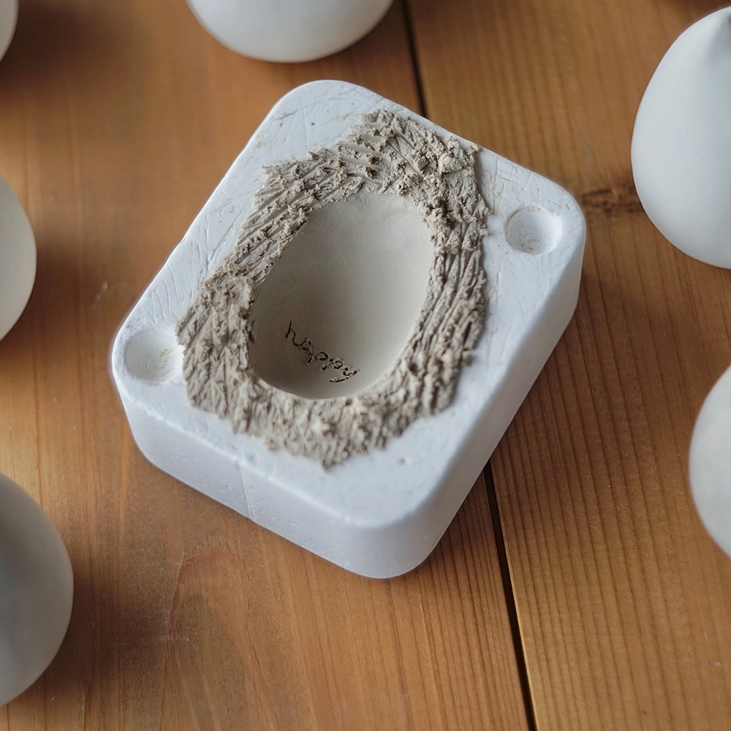 陶製フィギュアぽたねこの製造過程、石膏型に粘土をプレスしているところ